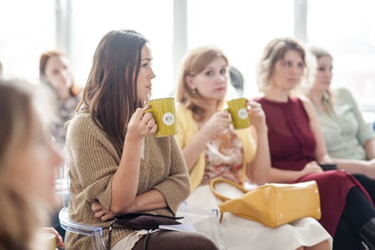 Image: Women sitting in a group, drinking coffee.
